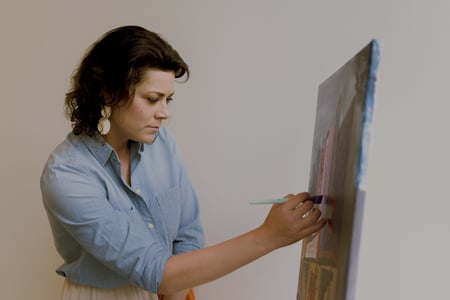 Woman painting on a canvas in her office.
