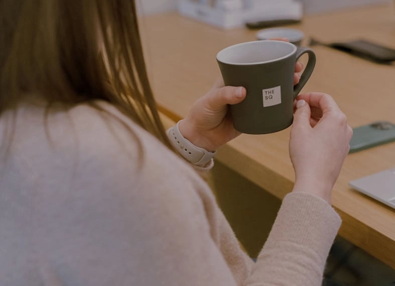 Woman holding Square branded mug sitting at the desk