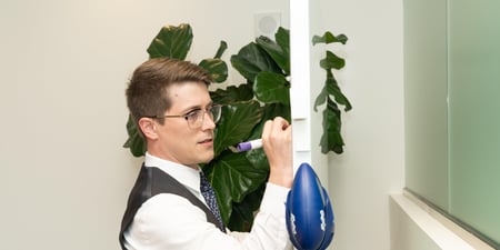 Man in suit writing on whiteboard in shared office space