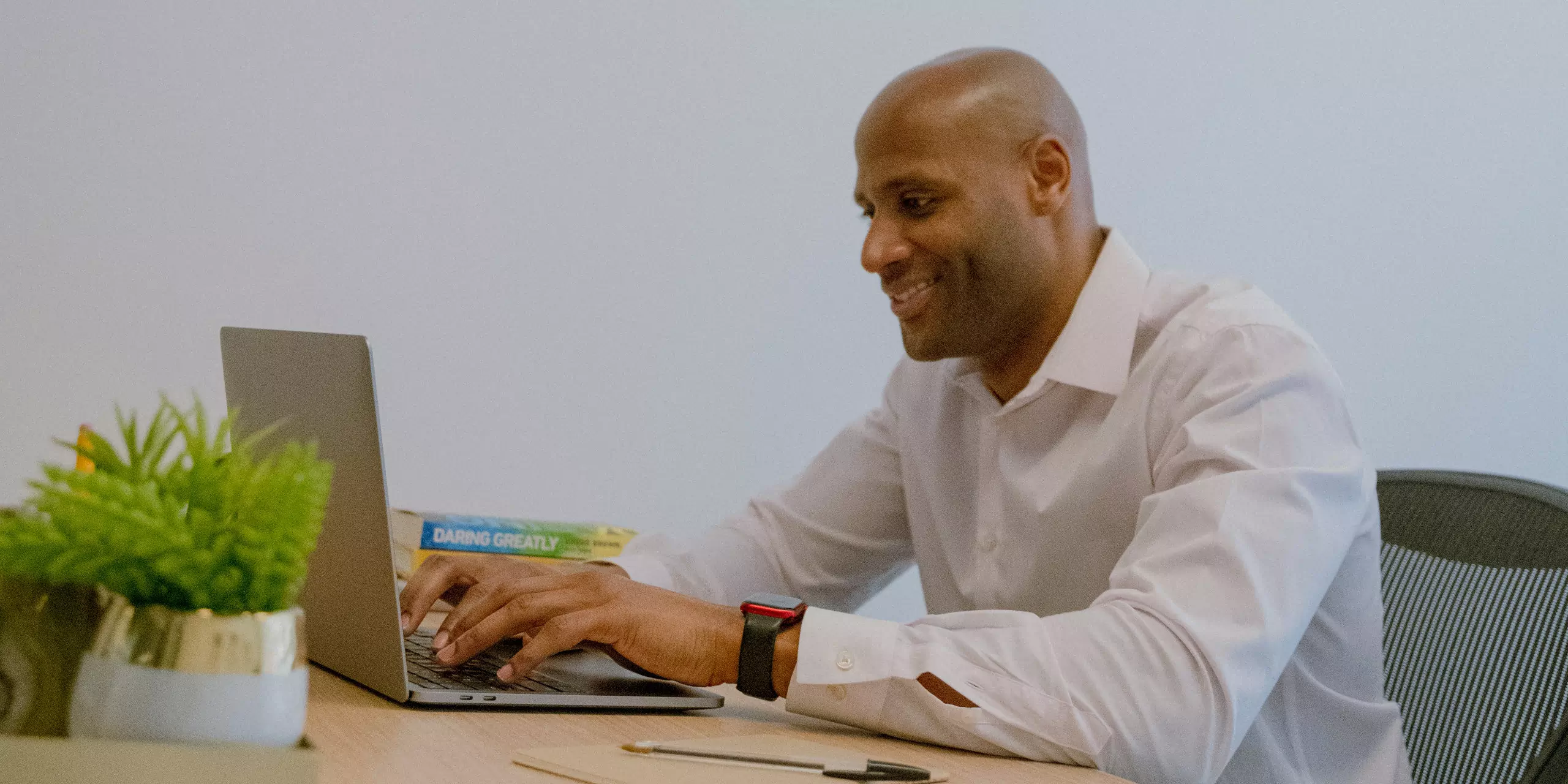 A man wearing smartwatch working on his laptop smiling
